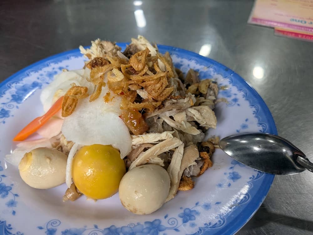 希少部位の「キンカン(trứng non:鶏の未成熟卵)」をトッピングした鶏おこわ。鮮やかな黄色のキンカンと数個の小さな卵がおこわに添えられた、濃厚な味わいが伝わる実食写真。