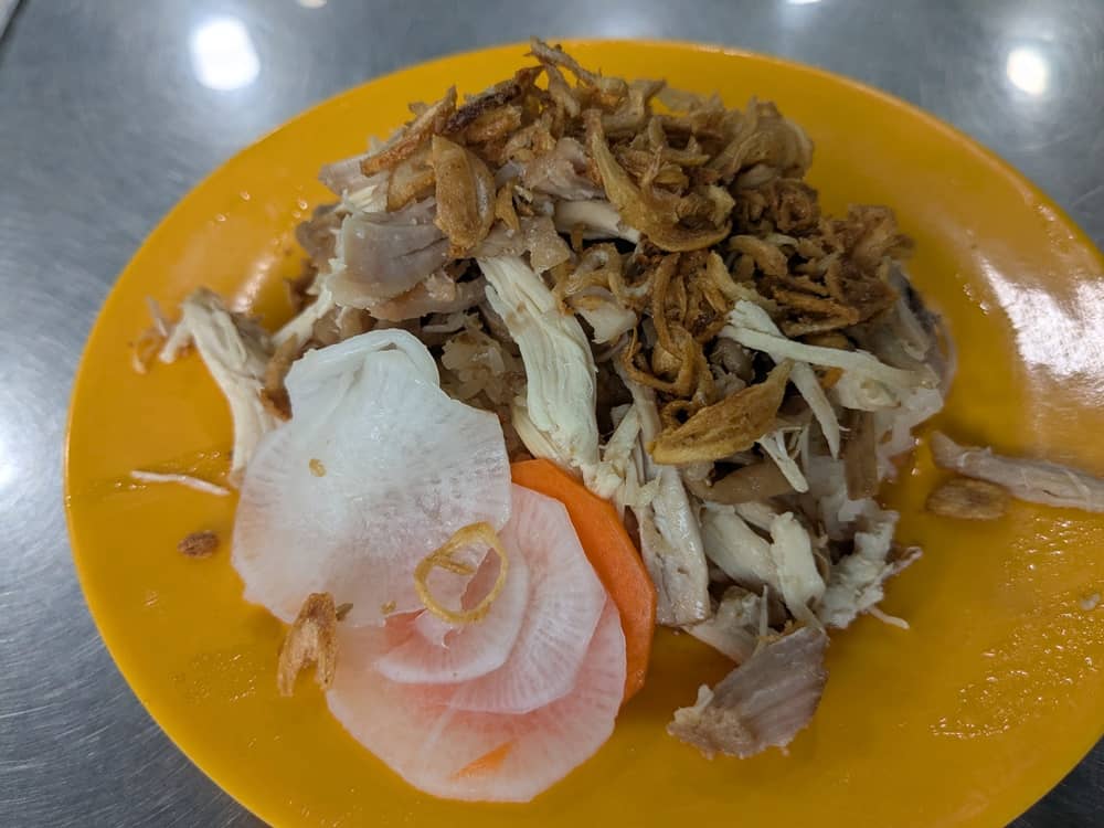 ソイガーナンバーワンの看板メニュー「鶏おこわ(Xôi gà)」。黄色いお皿に盛られたもちもちのおこわの上に、たっぷりの鶏肉、カリカリのフライドエシャロット、付け合わせのなます(大根と人参)が乗っている様子。