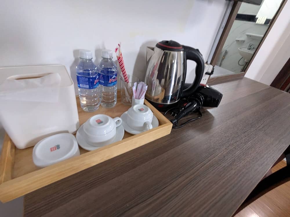 ドレッサーの上にポット、ドライヤー、ティーセット、水2本がある。