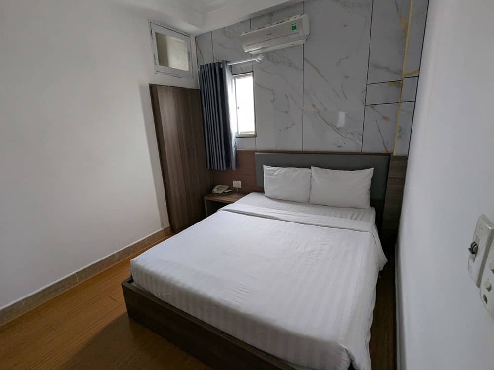 「ROSA HOTEL」の室内の様子。ダブルサイズベッドにクーラー、クローゼット、窓が見える