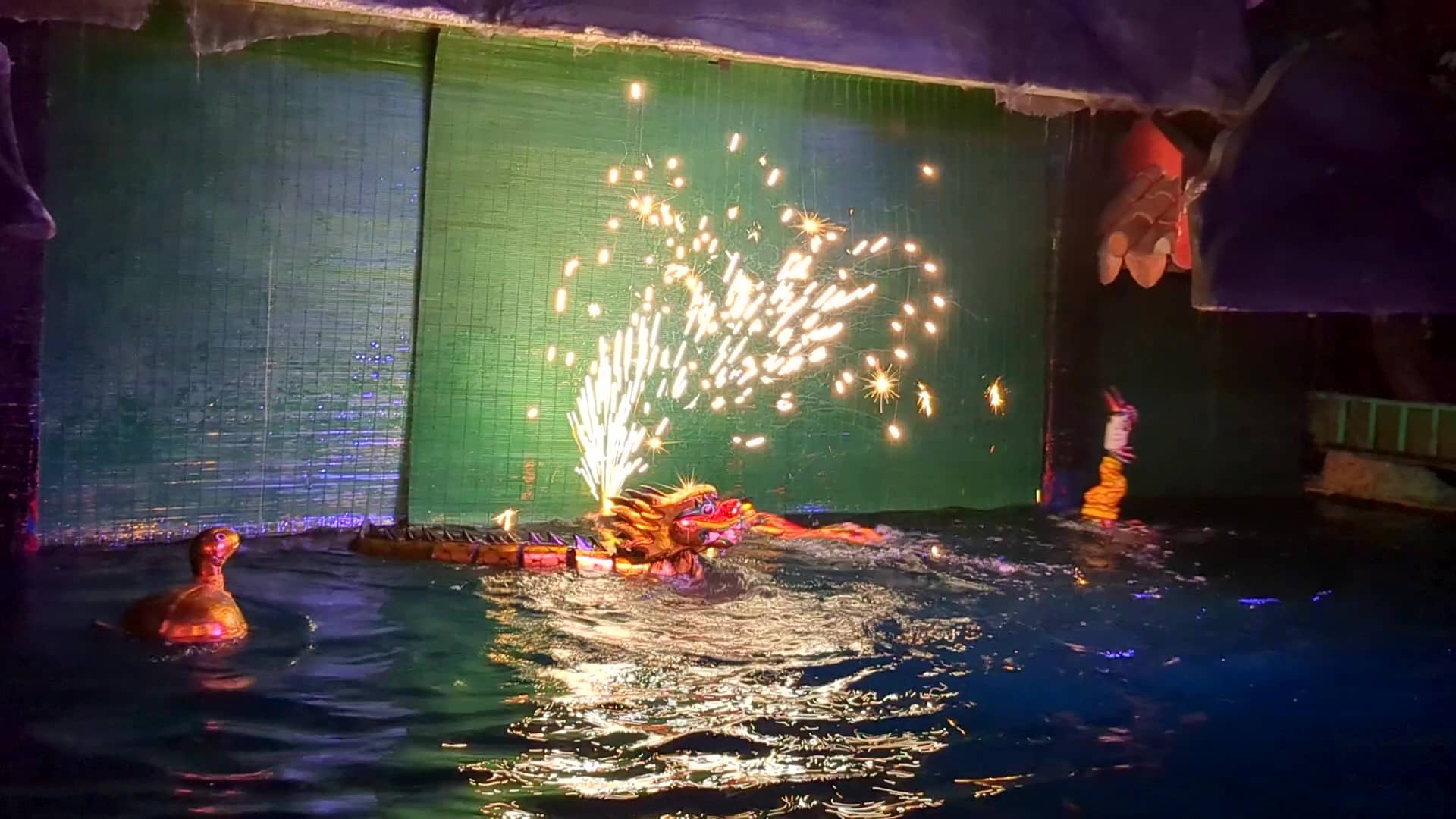 ホーチミン市歴史博物館の水上人形劇で、火花を吹き出しながら水面を泳ぐ龍の人形